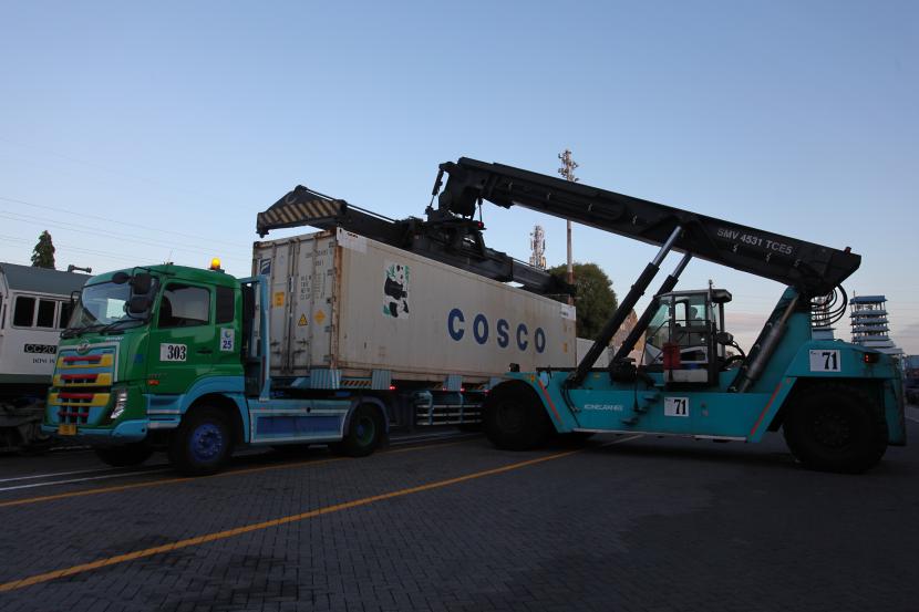 Operator alat berat memindahkan kontainer dari truk trailer di Terminal Petikemas Surabaya (TPS), Surabaya, Jawa Timur.