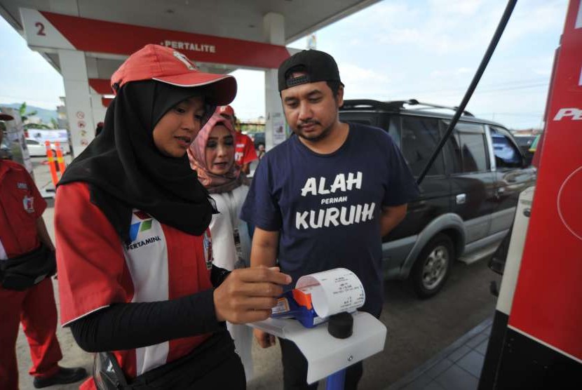 Operator membantu pengendara menggunakan kartu transaksi non tunai, untuk pembelian Bahan Bakar Minyak (BBM) di SPBU Pisang, Padang, Sumatera Barat, Rabu (19/9).