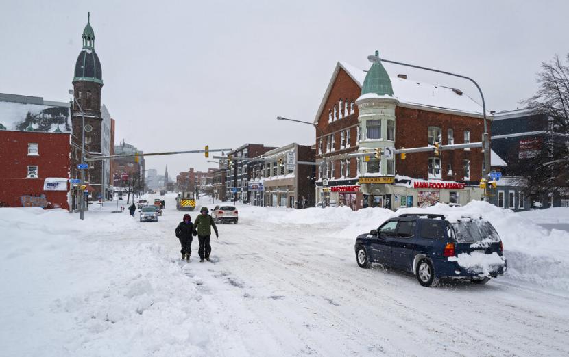 Orang dan kendaraan bergerak di sekitar Main St. di Buffalo, N.Y., Senin, 26 Desember 2022, setelah badai salju dahsyat menyelimuti kota. Seiring dengan drift dan larangan perjalanan, banyak jalan tidak dapat dilalui karena kendaraan yang ditinggalkan.