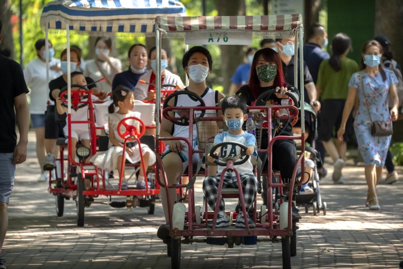 Orang dewasa dan anak-anak mengayuh sepeda di taman umum di Beijing, Sabtu, 21 Agustus 2021. China sekarang akan mengizinkan pasangan untuk memiliki anak ketiga karena negara itu berusaha untuk menahan krisis demografis yang mengancam harapannya akan peningkatan kemakmuran dan global pengaruh.