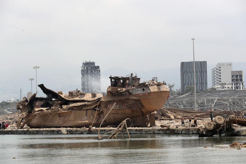 Orang-orang berdiri di dekat puing-puing kapal di lokasi ledakan yang hancur di pelabuhan Beirut, Lebanon, Kamis (6/8).