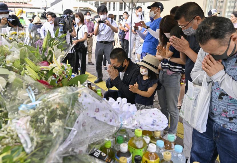  Orang-orang berdoa di sebuah peringatan darurat di dekat lokasi di mana mantan Perdana Menteri Shinzo Abe ditembak saat menyampaikan pidatonya untuk mendukung kandidat Partai Demokrat Liberal selama kampanye pemilihan di Nara, Sabtu, 9 Juli 2022.