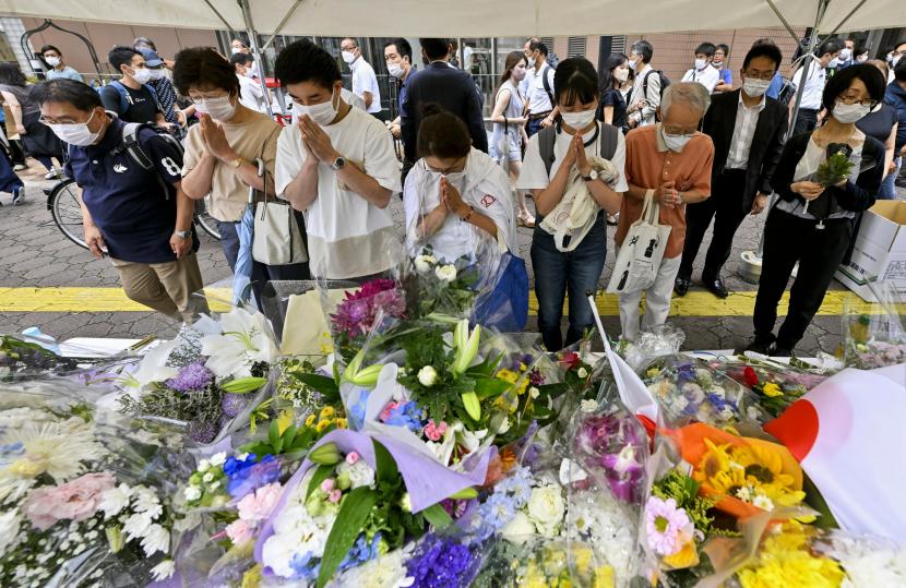  Orang-orang berdoa di tugu peringatan darurat di dekat lokasi di mana mantan Perdana Menteri Shinzo Abe ditembak mati saat menyampaikan pidatonya untuk mendukung kandidat Partai Demokrat Liberal selama kampanye pemilihan hari Jumat di Nara, Sabtu, 9 Juli 2022. 