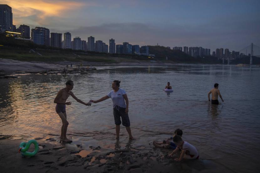Orang-orang berenang di air dangkal dekat dasar sungai kering Sungai Yangtze di Kotamadya Chongqing, China barat daya, Jumat, 19 Agustus 2022.