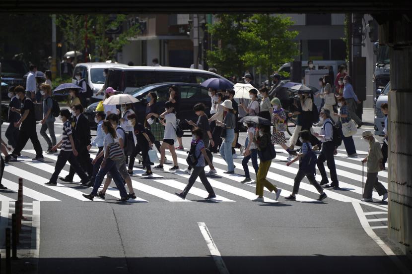Orang-orang berjalan di atas penyeberangan pejalan kaki di bawah terik matahari Senin, 30 Mei 2022, di Tokyo. Cuaca panas pada hari Senin telah ditetapkan dengan suhu naik lebih dari 27 derajat Celcius (80,6 derajat Fahrenheit) di Tokyo, menurut Badan Meteorologi Jepang.