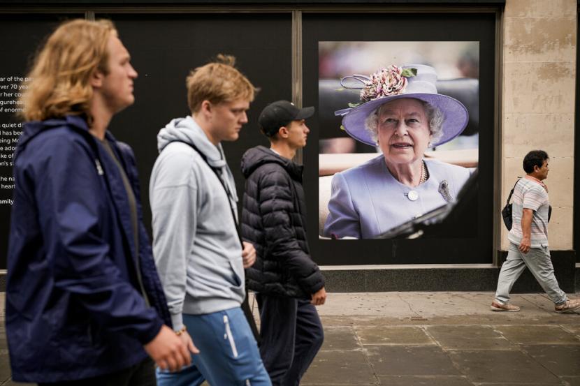 Orang-orang berjalan di dekat potret Ratu Elizabeth II di pusat kota London, Selasa, 13 September 2022. Ratu Elizabeth II, raja terlama yang memerintah Inggris dan batu stabilitas di sebagian besar abad yang bergejolak, meninggal Kamis 8 September 2022, setelah 70 tahun bertahta, pada usia 96 tahun.