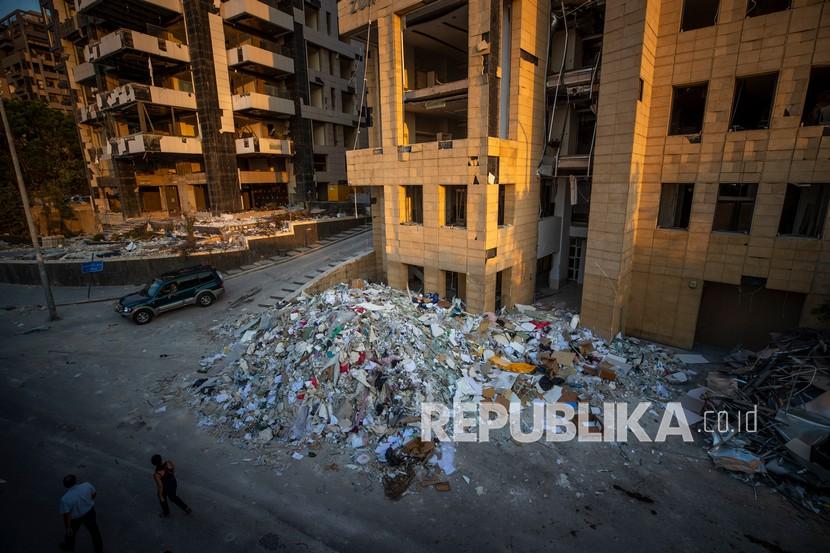 Militer Lebanon Temukan 4,35 Ton Amonium Nitrat. Orang-orang berjalan di dekat puing-puing bangunan yang hancur di dekat lokasi ledakan yang melanda pelabuhan Beirut, Lebanon Agustus lalu.