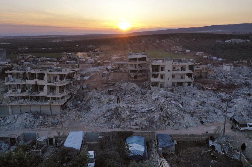 Orang-orang berjalan melewati bangunan yang runtuh setelah gempa dahsyat di kota Jinderis, provinsi Aleppo, Suriah, Kamis, 9 Februari 2023. Gempa yang menghancurkan ribuan bangunan itu merupakan salah satu yang paling mematikan di dunia dalam lebih dari satu dekade. Arab Saudi Tawarkan Bantuan Kesehatan Virtual untuk Korban Gempa Turki-Suriah