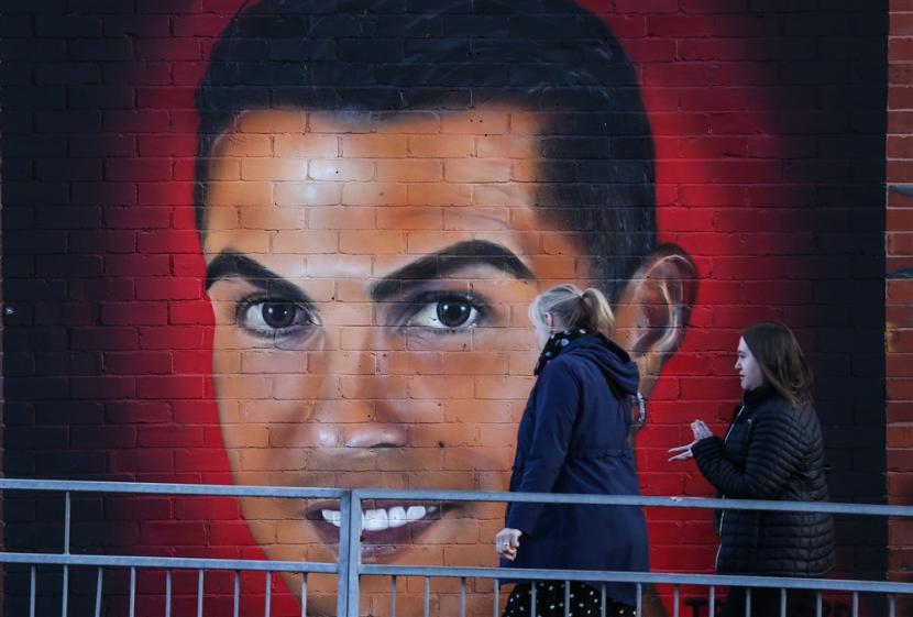  Orang-orang berjalan melewati mural mantan pemain Manchester United Cristiano Ronaldo di dekat Old Trafford di Manchester, Inggris, 23 November 2022.