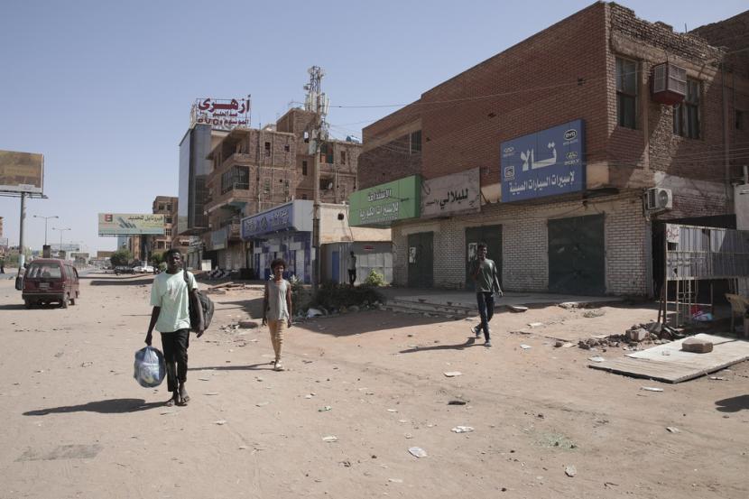 Orang-orang berjalan melewati toko-toko yang tutup di Khartoum, Sudan. Perang militer masih terjadi di Sudan dengan multiefek 