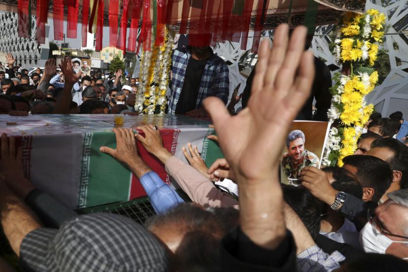 Orang-orang berkabung di sebelah peti mati terbungkus bendera Pengawal Revolusi Iran Kolonel Hassan Sayyad Khodaei yang terbunuh pada hari Minggu, dalam upacara pemakamannya di Teheran, Iran, Selasa, 24 Mei 2022.
