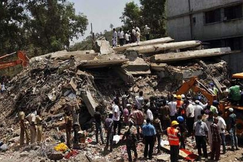 Orang-orang berkerumun di dekat gedung yang runtuh di Mumbai, India, saat tim penyelamat berusaha mengevakuasi korban.