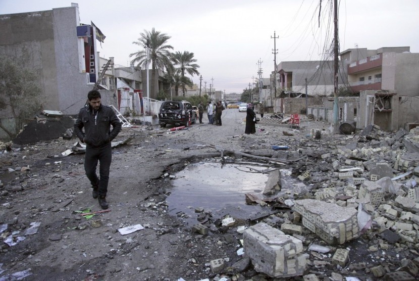 Orang-orang berkumpul dengan ceruk bekas bom mobil di New Baghdad, Irak