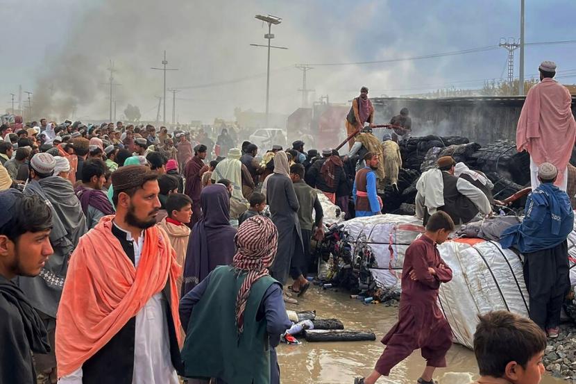 Orang-orang berkumpul di samping truk yang terbakar akibat penembakan pasukan Afghanistan, di Chaman, sebuah kota di barat daya Pakistan di sepanjang perbatasan Afghanistan, Minggu, 11 Desember 2022. Militer Pakistan mengutuk 