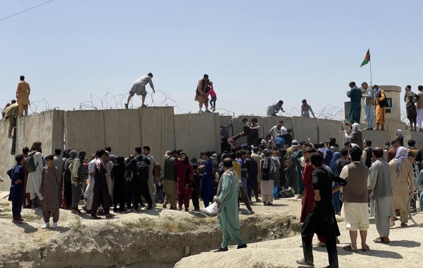  Orang-orang berusaha melintasi tembok perbatas Bandara Internasional Hamid Karzai untuk melarikan diri dari Afghanistan menyusul maraknya desas-desus bahwa negara-negara asing mengevakuasi orang-orang, bahkan tanpa visa, setelah Taliban menguasai Kabul, Afghanistan, 16 Agustus 2021.
