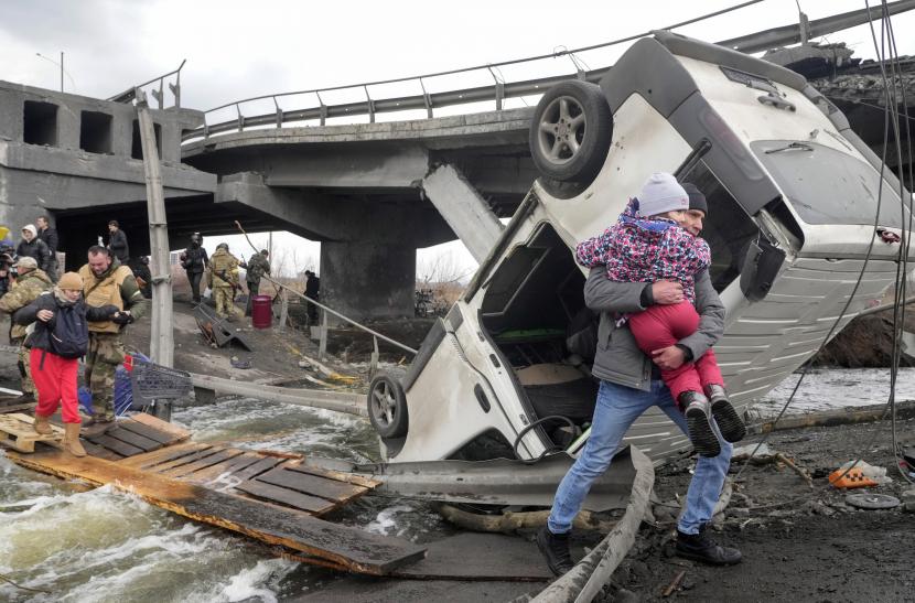Orang-orang melintasi jalan darurat di bawah jembatan yang hancur saat melarikan diri dari kota Irpin dekat Kyiv, Ukraina, Senin, 7 Maret 2022. Bank Dunia telah menyetujui paket dukungan sebesar 723 juta dolar AS untuk Ukraina, Senin (7/3/2022).