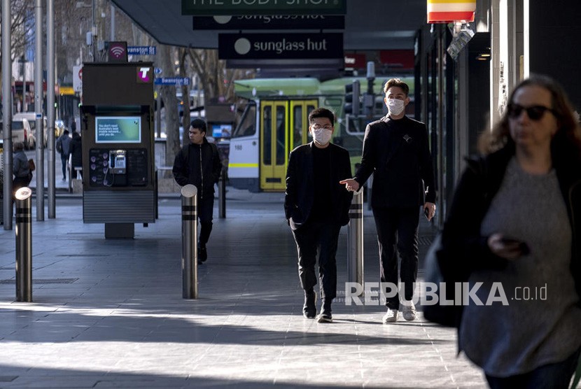  Orang-orang memakai masker berjalan di Melbourne, Australia. Negara bagian Victoria semakin memperketat aturan karantina pasien Covid-19. Ilustrasi.