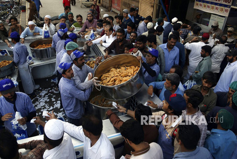 Orang-orang membeli makanan Iftar atau makanan berbuka puasa di sebuah masjid di Karachi Pakistan, Selasa, (7/5/2019). 