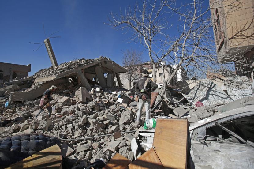 Orang-orang memeriksa puing bangunan yang rusak akibat serangan udara di Sanaa, Yaman, Selasa (18/1/2022).