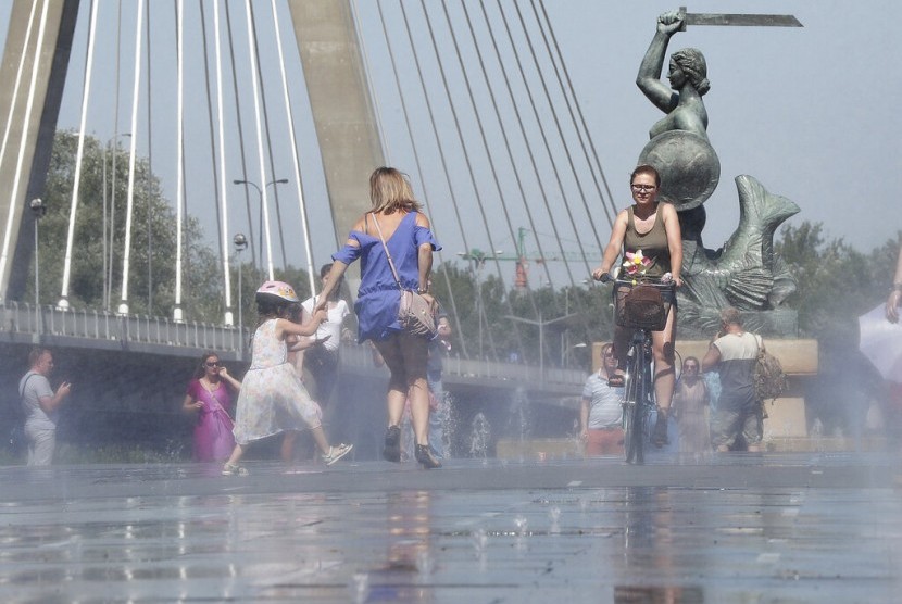 Orang-orang mendinginkan diri di Sungai Vistula saat gelombang panas menyerang Warsawa, Polandia, Ahad (30/6). 