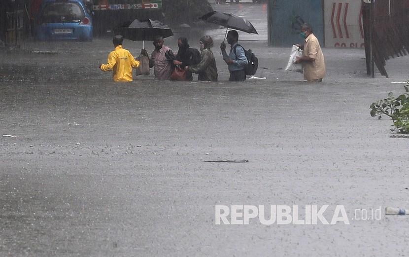 Orang-orang menerobosi jalan yang banjir setelah bus mereka mogok saat hujan lebat di Mumbai, India, Rabu (15/7/2020). 