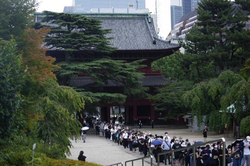 Orang-orang mengantre sebelum berdoa untuk menghormati mantan Perdana Menteri Jepang Shinzo Abe di kuil Zojoji sebelum pemakamannya di Tokyo pada Selasa, 12 Juli 2022. Abe dibunuh Jumat saat berkampanye di Nara, Jepang barat.
