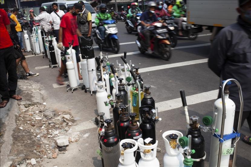 Orang-orang mengantre untuk mengisi ulang tangki oksigen mereka di sebuah stasiun pengisian oksigen di Jakarta.  Polda Metro Jaya ungkap penimbun obat-obatan avigan, ivermectin, dan tabung oksigen