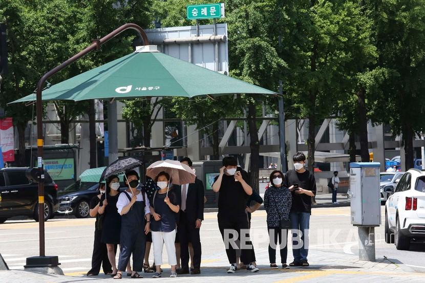  Orang-orang mengenakan masker menunggu untuk menyeberang jalan di Seoul, Korea Selatan, Kamis (11/6). 