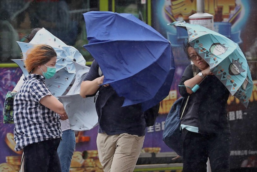 Orang-orang menyeberang jalan saat hujan deras dan angin kencang yang dibawa oleh badai di Taipei, Taiwan.