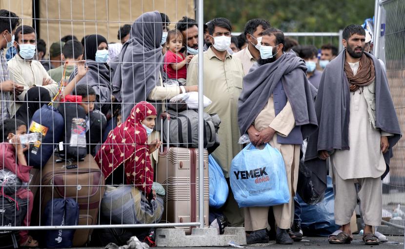  Orang-orang tinggal di dekat pagar Pangkalan Udara AS Ramstein di Ramstein, Jerman, Senin, 30 Agustus 2021. Komunitas militer Amerika terbesar di luar negeri menampung ribuan pengungsi Afghanistan di sebuah kota tenda di pangkalan udara. 