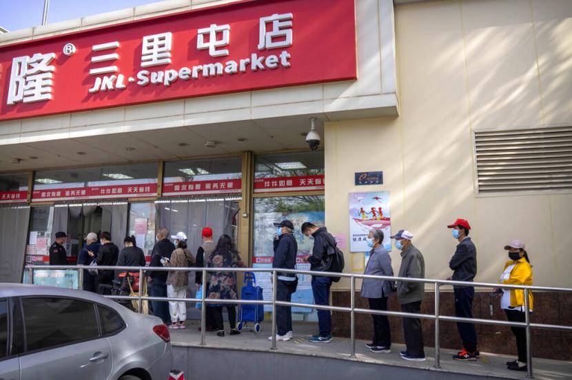 Orang-orang yang memakai masker berbaris di luar supermarket di Beijing, Selasa, 26 April 2022. Beijing akan melakukan pengujian massal terhadap sebagian besar dari 21 juta orangnya, pihak berwenang mengumumkan Senin, ketika wabah COVID-19 baru memicu penimbunan makanan oleh penduduk yang khawatir tentang kemungkinan penguncian gaya Shanghai.