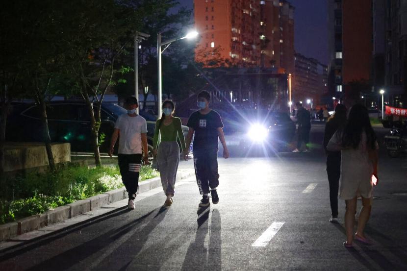 Orang-orang yang memakai masker berjalan di sepanjang jalan di dalam komunitas perumahan di Shanghai, Cina, Senin, 11 April 2022.  Kota Shanghai lockdown sejak pertengahan Maret 2022 karena memburuknya pandemi.