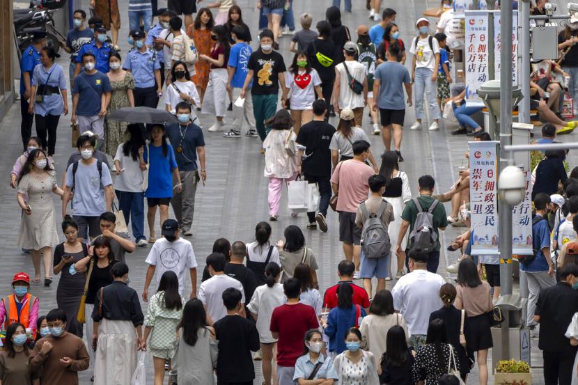 Orang-orang yang memakai masker berjalan di sepanjang jalan perbelanjaan luar ruangan di Beijing, China, Sabtu, 27 Agustus 2022. Guangzhou dan Shenzhen, China, memberlakukan pembatasan sosial Covid-19 di sebagian kota.