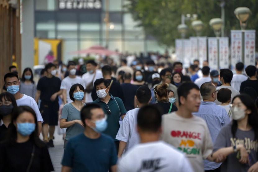 Orang-orang yang memakai masker berjalan melalui area perbelanjaan luar ruangan di Beijing, Sabtu, 17 September 2022. Organisasi Kesehatan Dunia (WHO) mengatakan, Covid-19 tetap menyandang status sebagai darurat global kesehatan.
