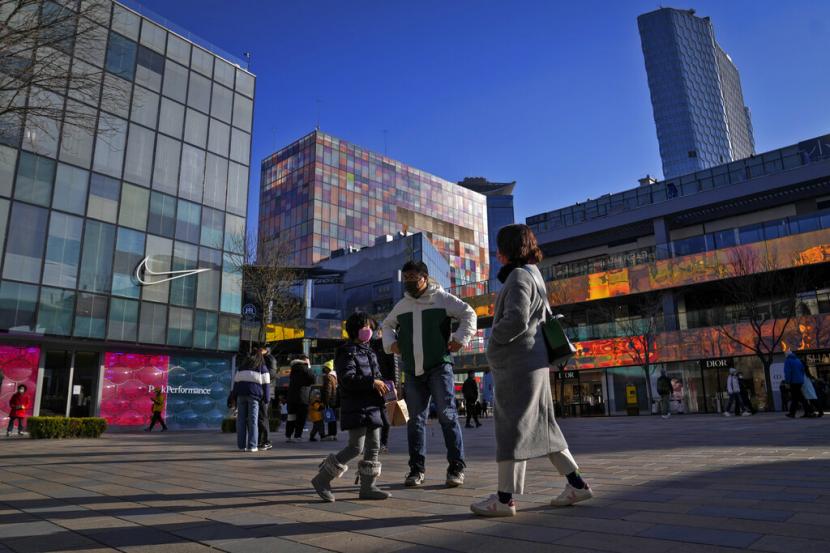 Orang-orang yang memakai masker berjalan melalui pusat perbelanjaan terbuka yang dibuka kembali di Beijing, Minggu, 4 Desember 2022. 