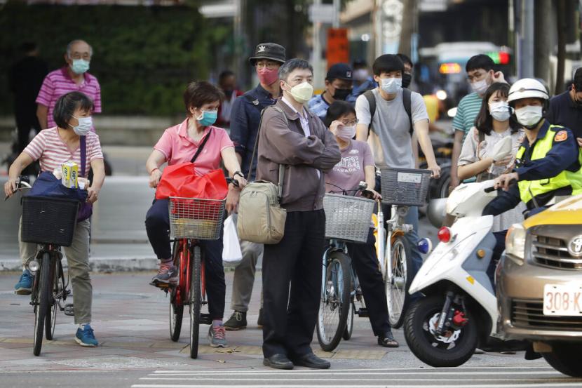 Orang-orang yang memakai masker untuk melindungi diri dari penyebaran virus corona menunggu untuk menyeberang jalan di Taipei, Taiwan, Rabu, 13 April 2022. Taiwan melaporkan kematian pertama seorang anak berusia dua tahun karena Covid-19 pada Selasa (19/4/2022) waktu setempat.