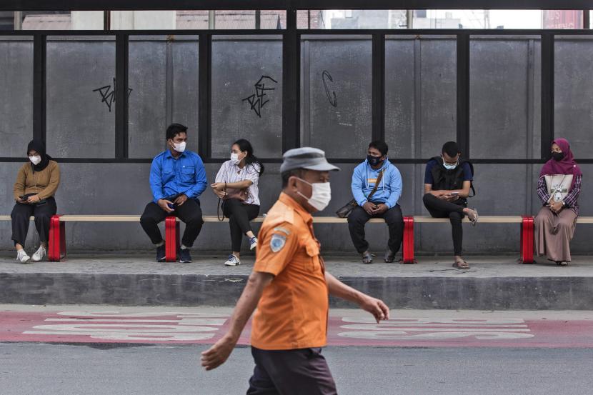Orang-orang yang memakai masker untuk membantu mengekang penyebaran wabah COVID-19 duduk di halte bus di Medan, Sumatera Utara, Sabtu, 29 Januari 2022. 