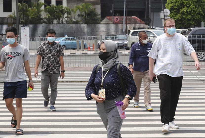 Orang-orang yang memakai masker berjalan di sepanjang penyeberangan pejalan kaki di kawasan bisnis utama di Jakarta, Indonesia, Kamis, 16 Desember 2021. Ada beragam situasi yang dapat membuat seseorang tertular Covid-19. 
