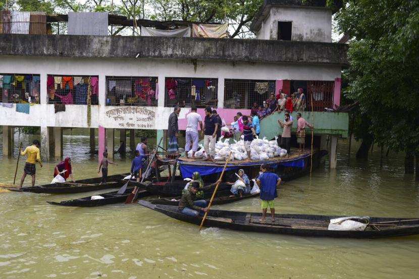 Orang-orang yang terkena dampak banjir menerima bahan bantuan di Companygonj di Sylhet, Bangladesh, Senin, 20 Juni 2022. Banjir di Bangladesh terus mendatangkan malapetaka pada hari Senin dengan pihak berwenang berjuang untuk mengangkut air minum dan makanan kering ke tempat penampungan banjir di seluruh wilayah utara dan timur laut yang luas di negara itu.