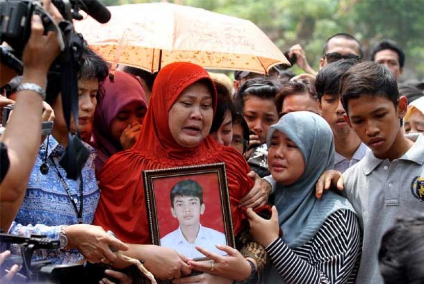  Orang tua almarhum Alawy Yusianto, Ibu Endang Puji (tengah) menyaksikan prosesi pemakaman anaknya Alawy Yusianto di pemakaman Poncol, Pudurenan, Tangerang, Banten, Selasa (25/9). 
