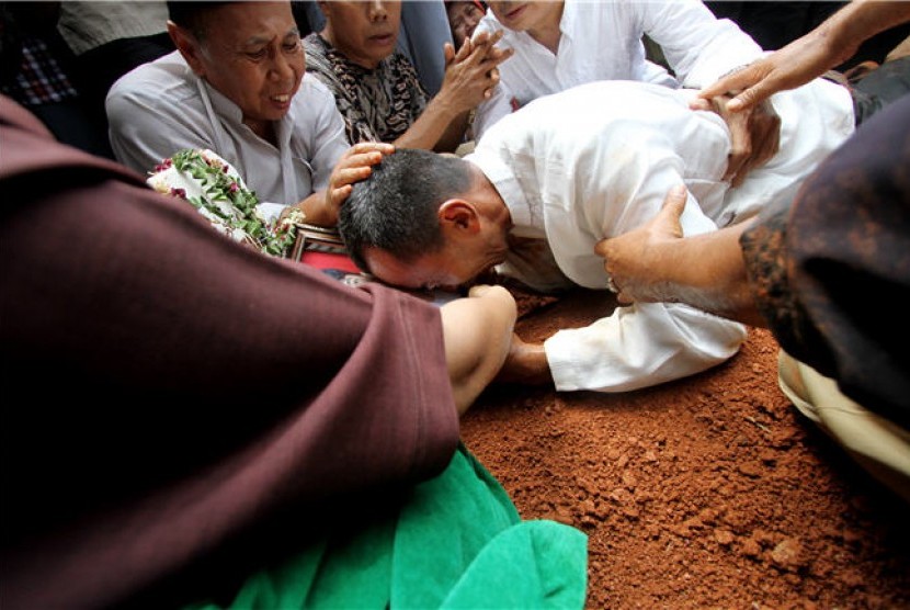  Orang tua almarhum Alawy Yusianto, Tauri Yusianto, memeluk dan menangisi foto anaknya Alawy Yusianto ketika pemakaman almarhum Alawy Yusianto di pemakaman Poncol, Pudurenan, Tangerang, Banten, Selasa (25/9). 