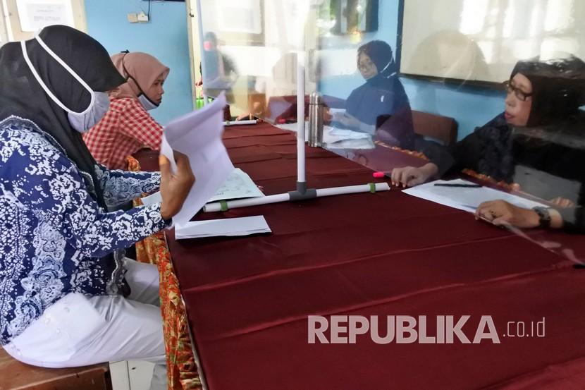 Orang tua calon siswa memegang berkas PPDB (Penerimaan Peserta Didik Baru) saat wawancara dan verifikasi pemeriksaan berkas di SMP Negeri 2 Serang, Banten, Senin (22/6/2020). Proses penerimaan peserta didik baru. (Ilustrasi)