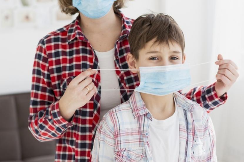Orang tua memakaikan anaknya masker (ilustrasi). Masker aman digunakan oleh anak yang mengidap asma selagi tidak sedang kambuh penyakitnya.