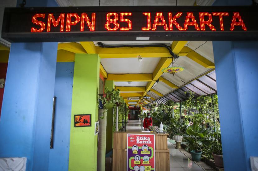 Orang tua murid melintas di SMP Negeri 85 Jakarta Selatan yang ditutup, Senin (25/7/2022). Sekolah tersebut ditutup selama 10 hari setelah tiga siswa terkonfirmasi Covid-19. Dinkes DKI memastikan PTM tetap dimungkinkan karena rasio kasus positif di sektor pendidikan masih di bawah lima persen. 