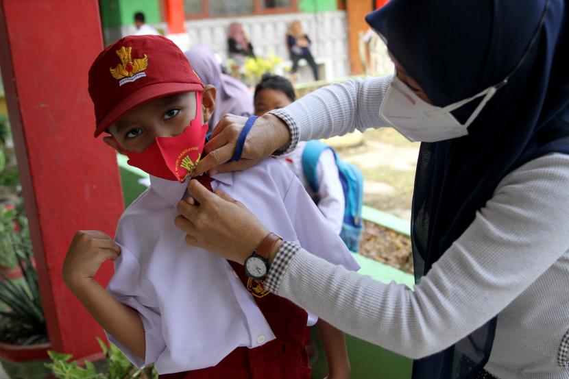 Orang tua murid merapikan seragam sekolah anaknya sebelum masuk ke dalam kelas di SD Negeri 10 Kendari, Kendari, Sulawesi Tenggara, Rabu (8/9/2021).  ilustrasi
