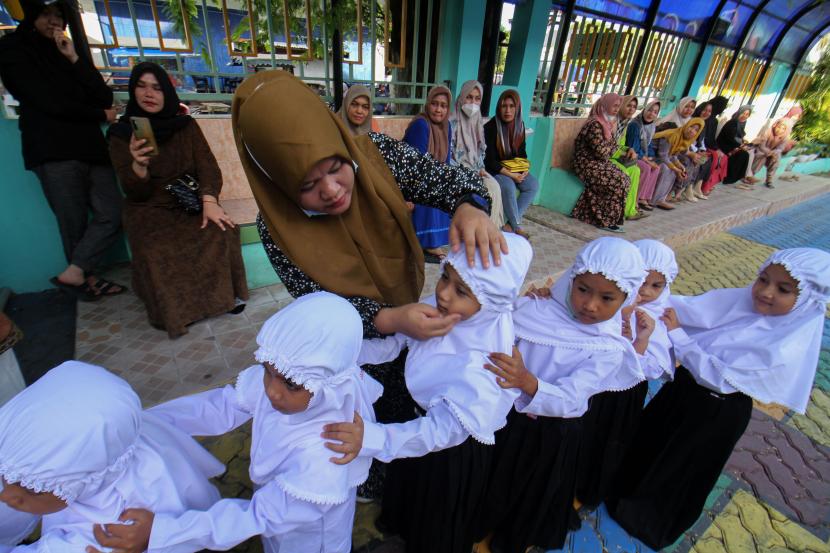 Orang tua siswa memperbaiki jilbab anaknya saat berlangsung perkenalan lingkungan bagi siswa baru. Wakil Ketua DPRD DIY sebut hal wajar guru minta siswa melakukan sesuatu demi kebaikan.