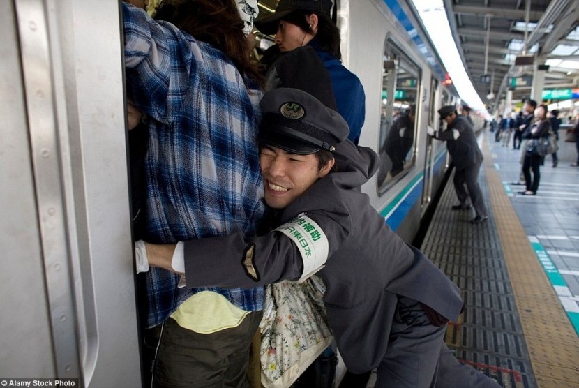 Oshiya sedang bekerja mendorong penumpang masuk ke kereta di Jepang.