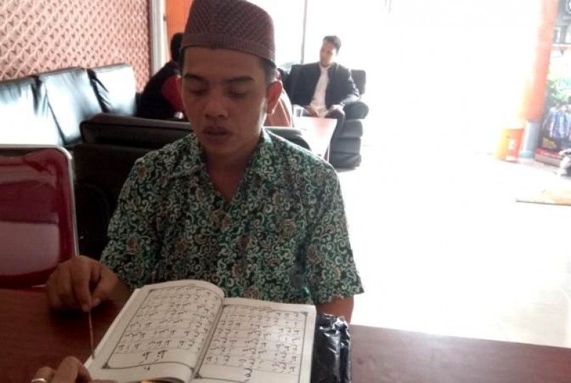 Pak Roni tengah belajar Iqra yang dibimbing pengajar dari PPPA Daarul Quran.
