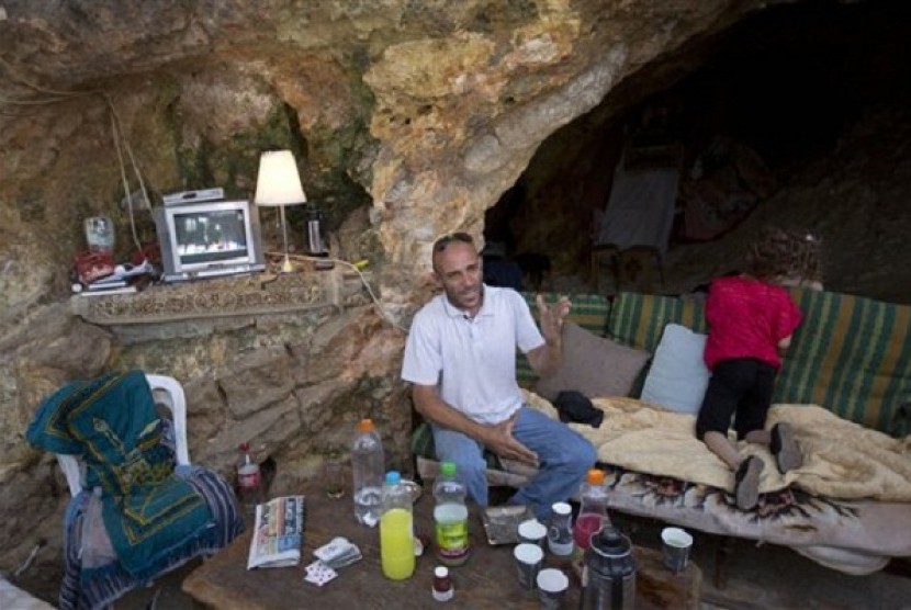 Palestinian Khaled Zir sits with his children inside a cave in the east Jerusalem neighborhood of Silwan, Tuesday, Aug. 27, 2013. Zir said the family moved into a cave after their home was demolished by Israeli authorities. 