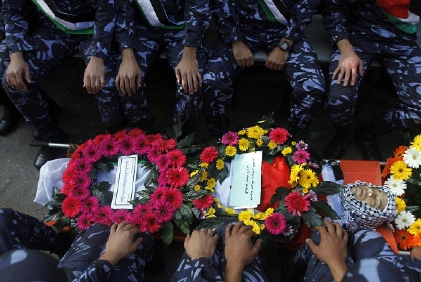 Palestinian policemen sit besides the body of their comrade Rushdi Tamimi (31 years), during his funeral procession in the West Bank city of Ramallah November 20, 2012. Residents said Tamimi died after he was shot in the stomach during a demonstration on S